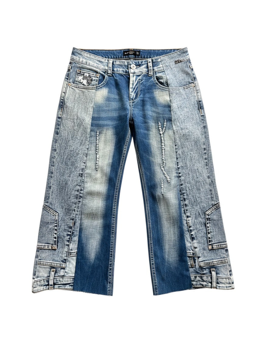 Thoughts Reworked blue denim jorts with distressed details and a patchwork design. These upcycled, one-off shorts feature a wide leg and frayed hem.